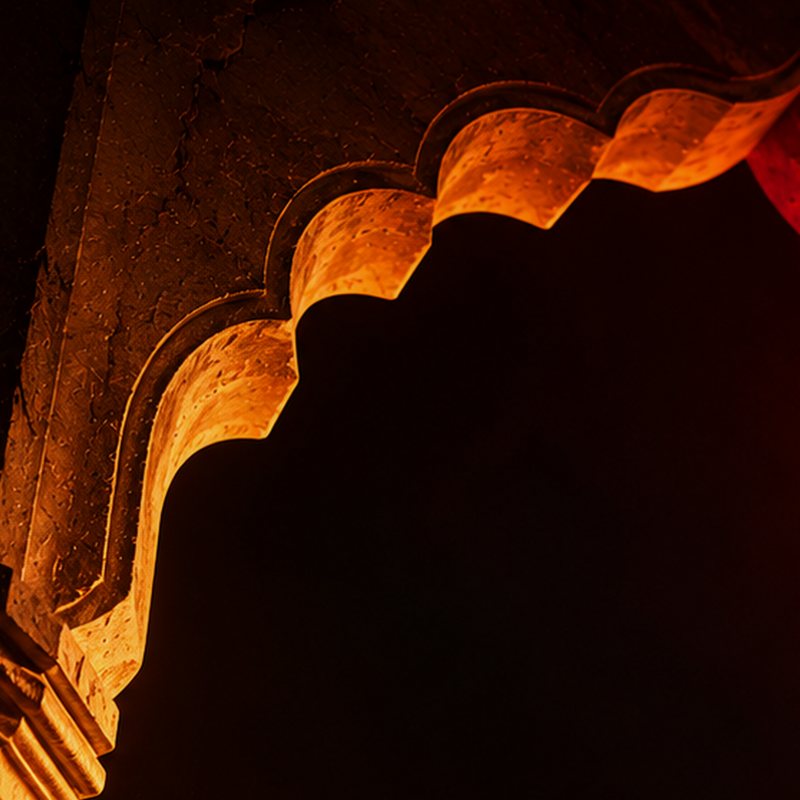 A glowing carved arch in amber and red, emerging from darkness