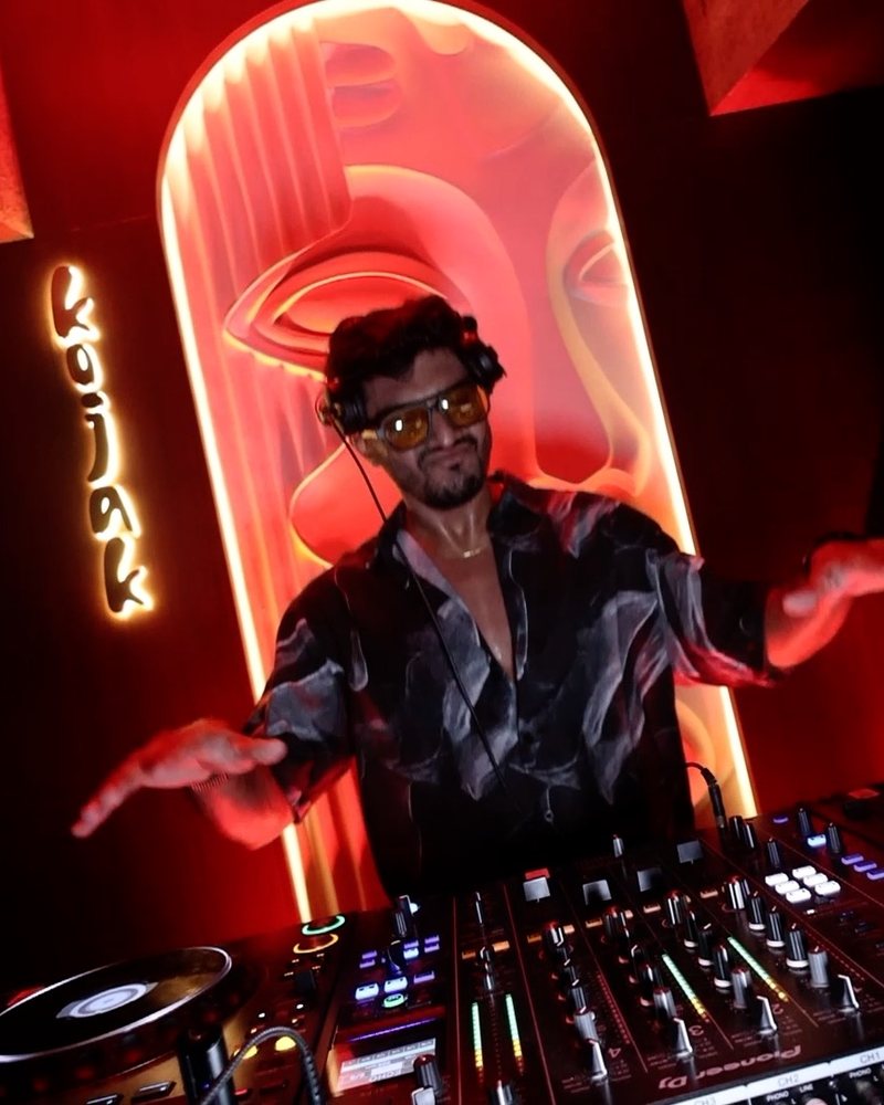 Aryan at the decks at Kojak, framed by a glowing red arch